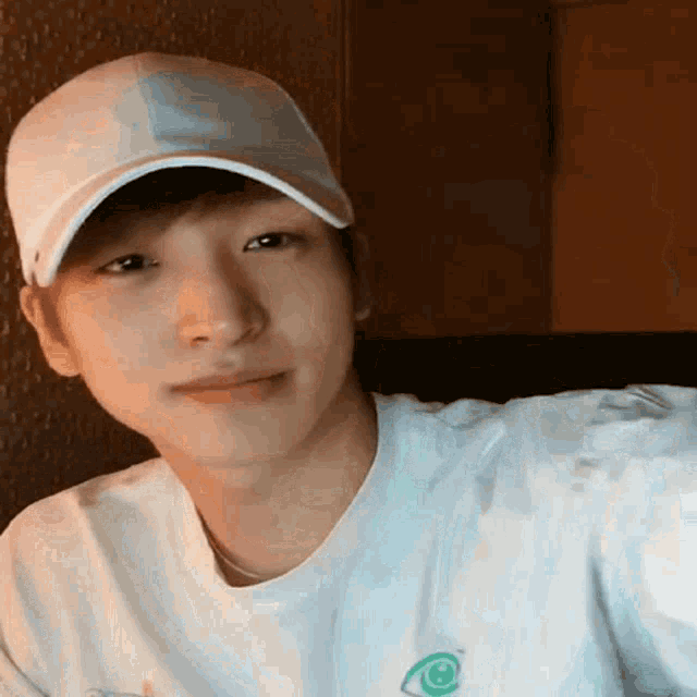a young man wearing a baseball cap and a white t-shirt is smiling .