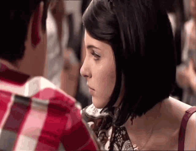 a man and a woman are looking at each other and the woman is wearing a scarf around her neck .