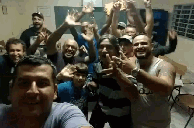 a group of men are posing for a picture with their hands up