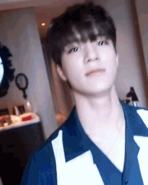 a young man is standing in a room wearing a blue and white striped shirt .