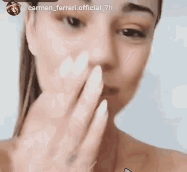 a woman is covering her mouth with her hand while looking at the camera .