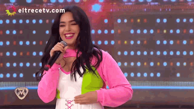 a woman singing into a microphone with eltrecetv.com on the bottom