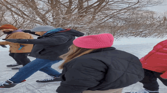 a woman wearing a pink hat and a black jacket is walking in the snow
