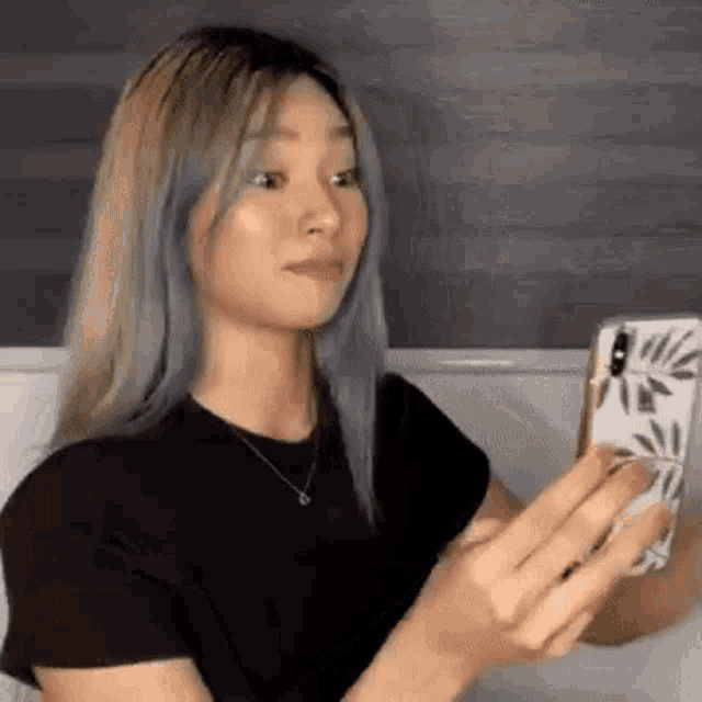 a woman is taking a picture of herself in a mirror with her phone .