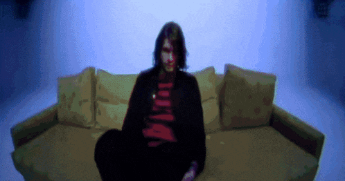 a pixelated image of a man sitting on a couch with a red shirt that says nirvana