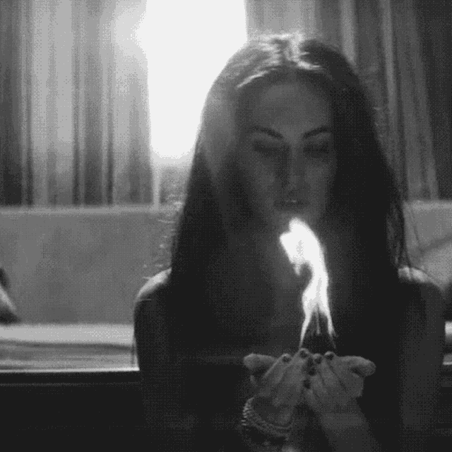 a black and white photo of a woman smoking a cigarette in a room .