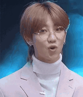 a young man wearing glasses and a turtleneck is making a face .