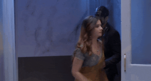 a man is holding a woman in his arms while they are dancing in a room .