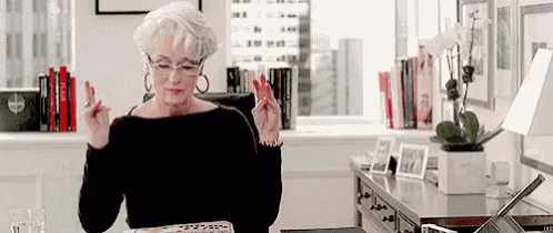 a woman wearing glasses is sitting at a desk in an office .