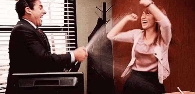 a man and a woman are having a fight in front of a computer screen .