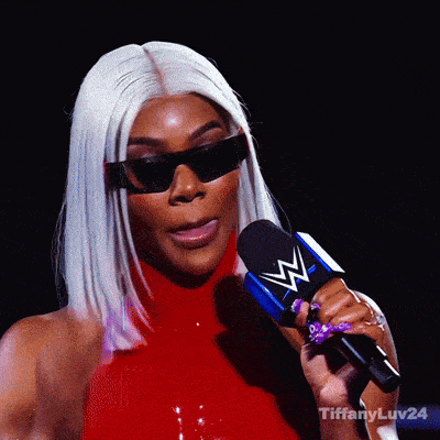 a woman wearing sunglasses and a red top is holding a microphone with a w logo on it