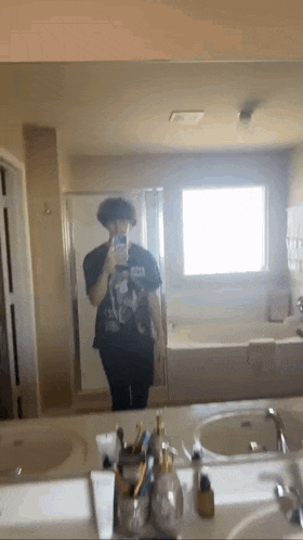 a person is taking a selfie in a bathroom mirror .