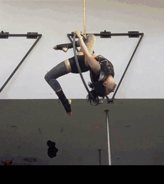 a woman is hanging upside down on a hoop