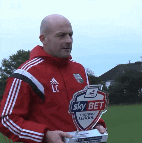 a man in a red adidas jacket is holding a trophy that says sky bet