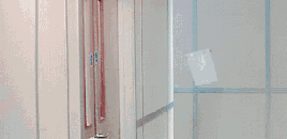 a man with blue hair is peeking out from behind a white wall .