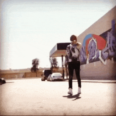 a person is walking in front of a building with graffiti on the side