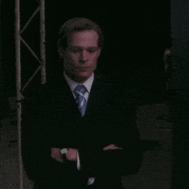 a man wearing a suit and tie with his arms crossed