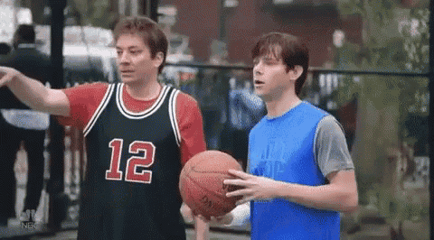 two men are playing basketball on a court . one of the men is wearing a jersey with the number 12 on it .
