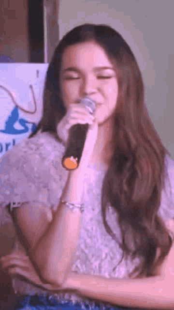 a woman with long hair is singing into a microphone