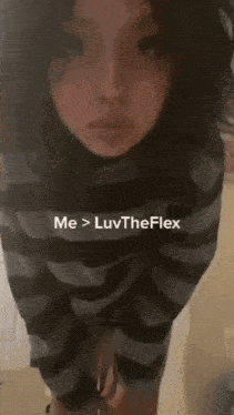 a woman in a striped shirt is standing in front of a wall with the words me > luvtheflex above her