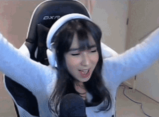 a girl wearing headphones is sitting in a chair with her arms outstretched .