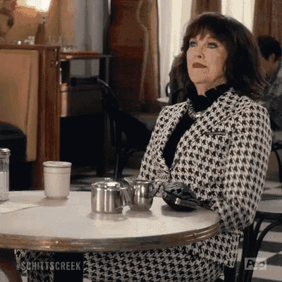 a woman in a black and white jacket is sitting at a table in a diner .