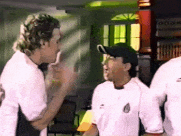 a group of men are standing in a room and one of them is wearing a white shirt with mexico on it