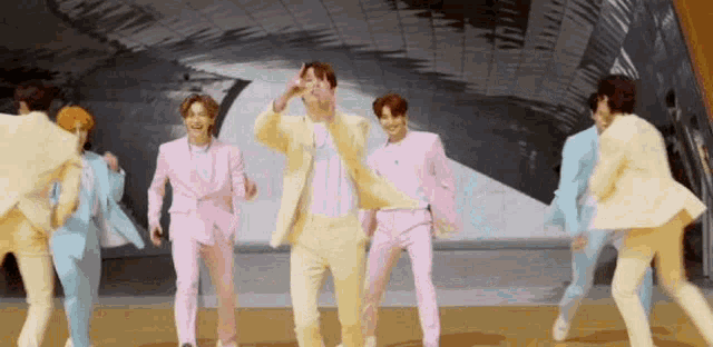 a group of men in suits are dancing on a stage in a room .