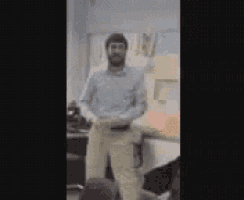 a man in a blue shirt and khaki pants is dancing in a room .