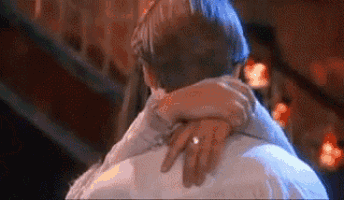 a man and a woman are hugging each other in a room .
