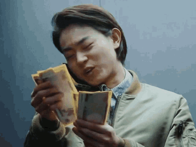 a man in a green jacket is holding a stack of money