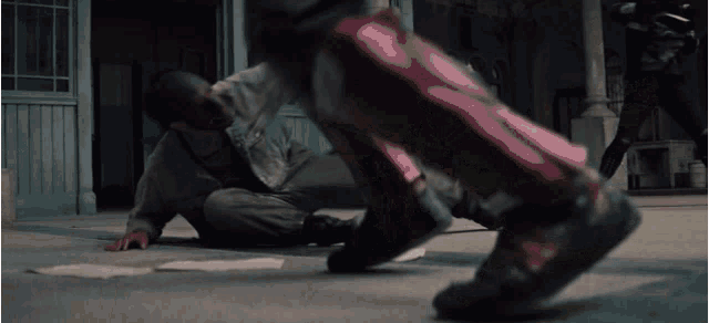 a man in a superhero costume is laying on the ground while another person kicks him