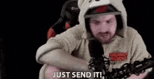 a man in a teddy bear costume is sitting in front of a microphone and says `` just send it '' .