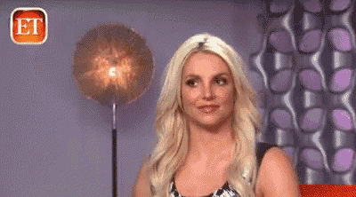 britney spears is making a funny face while standing in front of a lamp in a room .