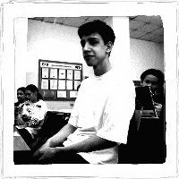 a man in a white shirt is sitting in a classroom with other students .