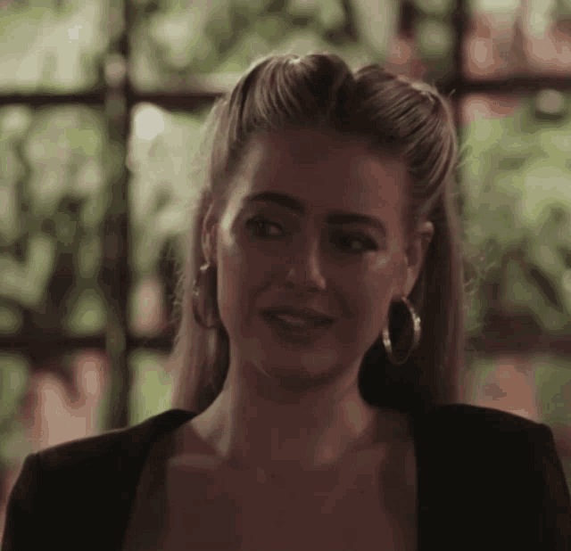 a close up of a woman wearing hoop earrings and a black top