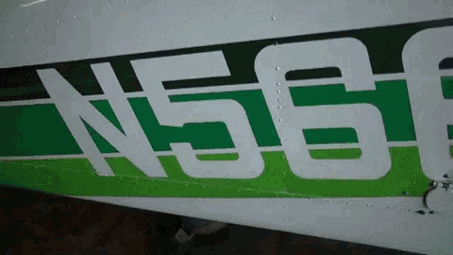a green and white airplane with the number n56f painted on the side
