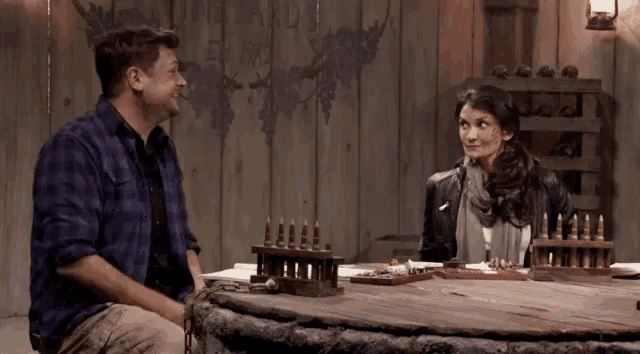 a man and a woman are sitting at a table in a room .