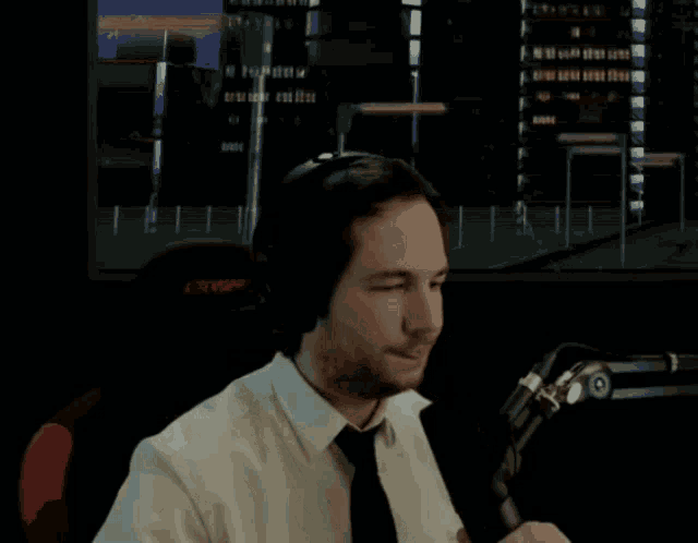 a man wearing headphones and a tie is saluting in front of a large screen