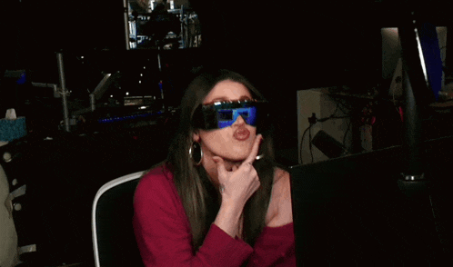 a woman wearing sunglasses is making a funny face while sitting in front of a laptop