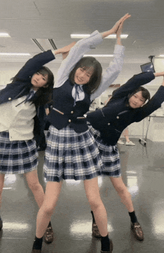 three girls in school uniforms stretch their arms