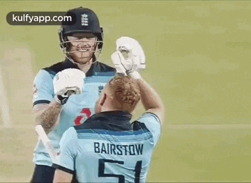 two cricket players are shaking hands on the field .