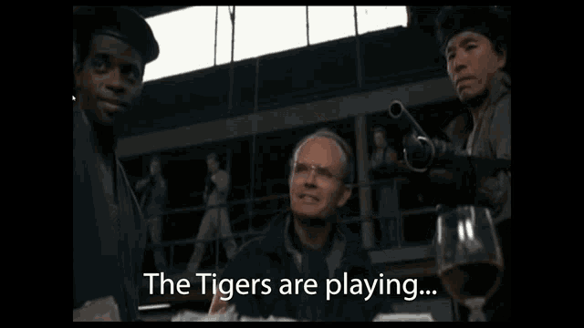 a man sitting at a table with a glass of wine and the words the tigers are playing