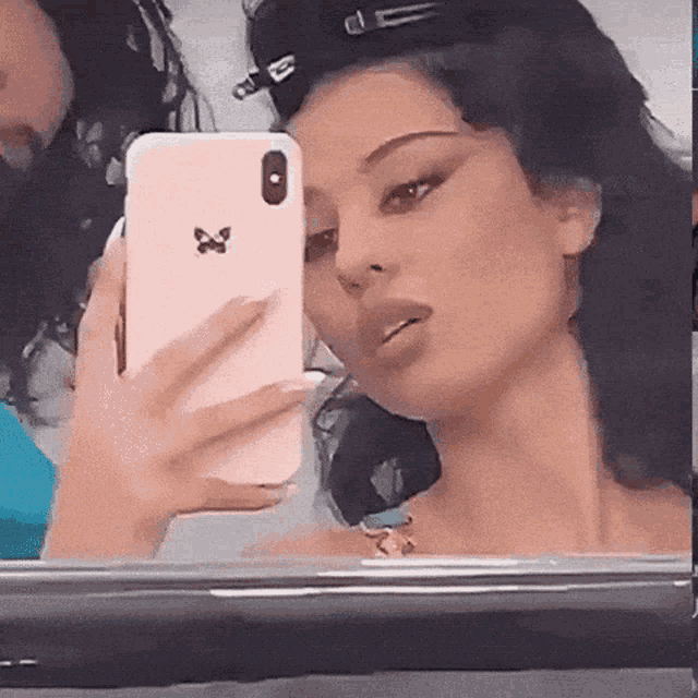 a woman is taking a picture of herself in a mirror with her phone .