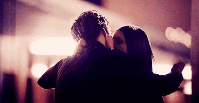 a man and a woman are kissing in a dark room