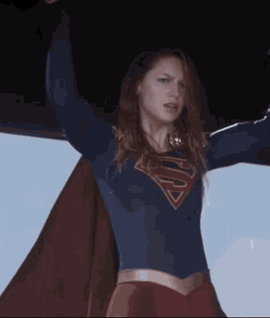 a woman in a superman costume holds her arms up in the air