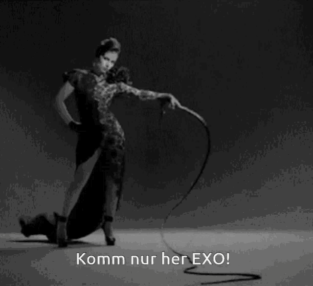 a black and white photo of a woman holding a whip with the words komm nur her exo on the bottom