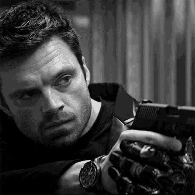 a man in a black shirt is holding a gun in his hand