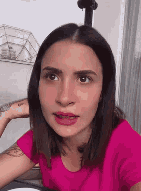 a woman in a pink shirt with a tattoo on her wrist