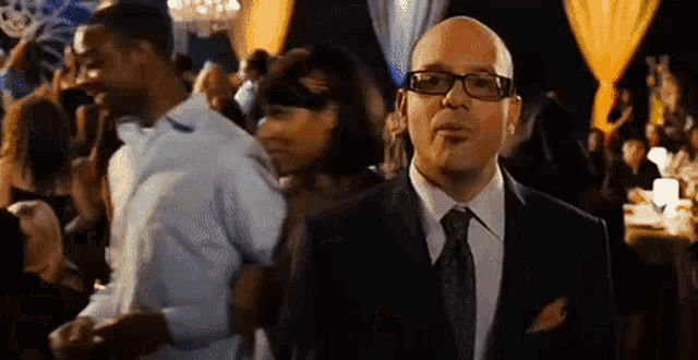 a man in a suit and tie is standing in a crowded room
